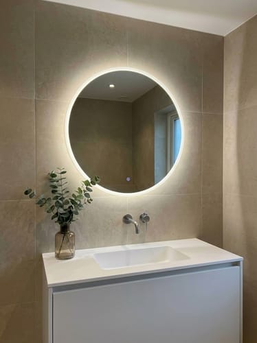 Avis d'un client montrant le miroir rond LED Genève allumé, installé dans une salle de bain moderne.