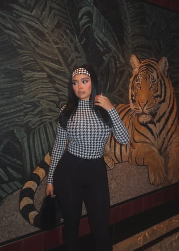Reviewer wearing the high-waisted black Naked Stirrup Legging, paired with a houndstooth top.