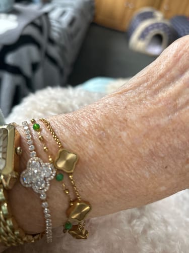 Customer wearing the textured gold Celine Clover Bracelet layered with other jewelry.