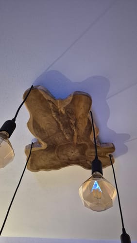 Rezensent zeigt die montierte NATURA Baumscheibe Deckenlampe mit rustikaler Holzscheibe und zwei Glühbirnen.