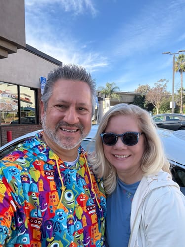 Reviewer smiling outdoors while wearing the colorful Monsters, Inc. performance hoodie with another person.