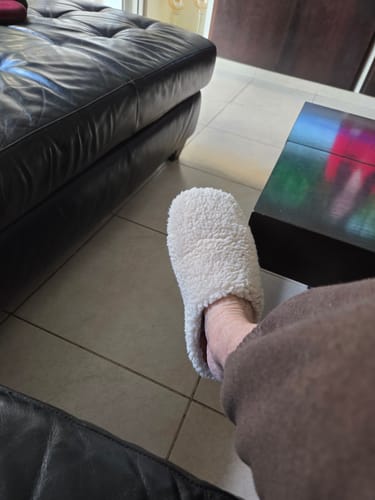 לקוחה נועלת את נעל הבית הפלאפית בצבע בז' בסלון.