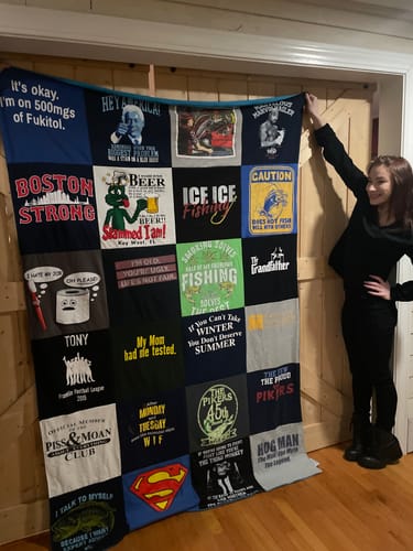 A reviewer holds up their large, colorful Premium T-Shirt Quilt made from memorable t-shirts.