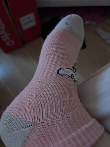 Närbild på kundens fot som bär en rosa Mumin Ankelstödstrumpa med grå häl och tå.