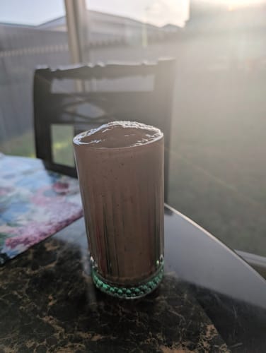Customer's fruit smoothie in a glass, made with Divine Woman Multivitamin Powder.