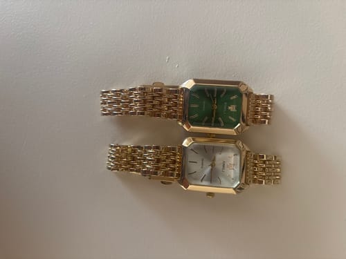 Customer's two CLAIRE DE MAINS watches with gold-colored bands, one with a green face and one with a white face.