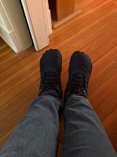 Customer's point-of-view wearing the dark Lorax Pro barefoot shoes indoors on a wood floor.