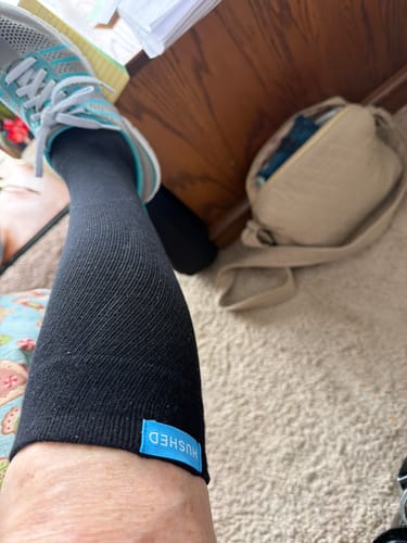Customer wearing the black Performance Eucalyptus Compression Sock, shown on their lower leg with a sneaker.