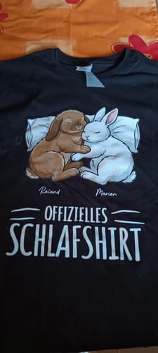 Ein Kunde zeigt sein personalisiertes schwarzes „Schlaf-Hasen“-T-Shirt mit einer Grafik von zwei schlafenden Hasen.