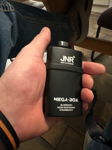Customer holding a black JNR Mega Box disposable vape, showing the Blueberry Sour Raspberry Strawberry flavor on the device.