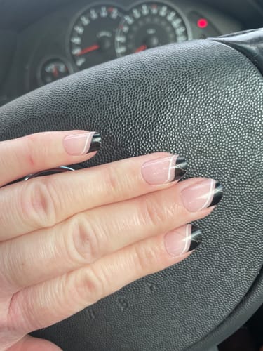Customer's hand on a steering wheel showing long nails with a stylish black and white design.