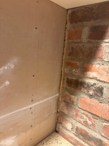 Reviewer shows a corner where drywall meets a brick wall, an area needing sanding with the Zirconia belts.