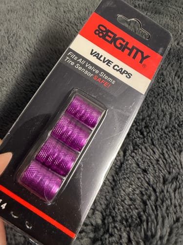Customer holding the unopened package of 80Eighty Purple Valve Stem Caps, showing the bright magenta color.