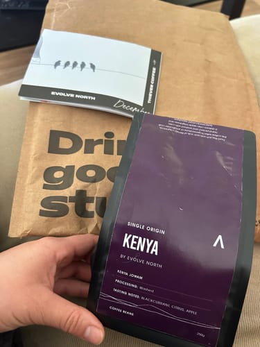 Reviewer holding their monthly coffee subscription delivery, featuring a bag of Kenya single-origin beans.