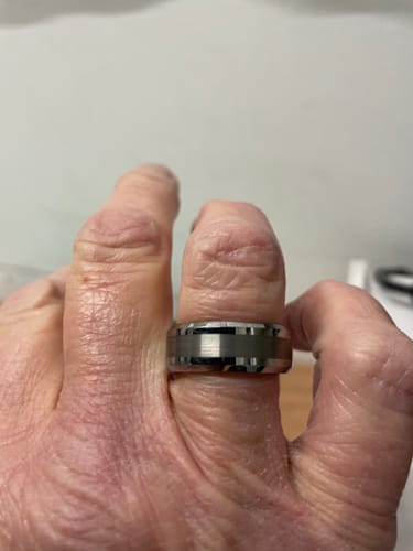 A reviewer's hand wearing the Alaric ring, showcasing its satin-brushed center and beveled edges.