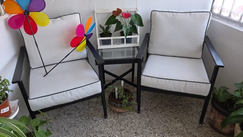 Foto de un cliente del juego de dos sillas para patio con cojines blancos, instaladas en un balcón con una mesita.