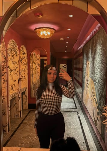 Reviewer wearing the houndstooth Naked Print Headband with a matching top while taking a mirror selfie.