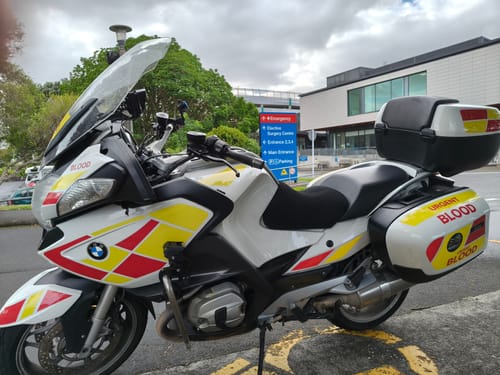 Customer's white emergency motorcycle with a black Wind Rider Seat Cover parked in front of a hospital.
