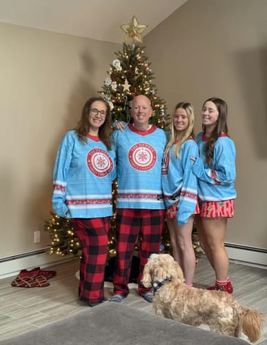 Customer's family wearing matching light blue Family Christmas Custom Hockey Jerseys while posing by a Christmas tree.