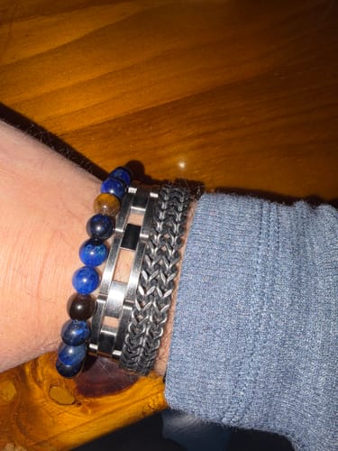 Customer wearing the blue beaded Nighthawk Tiger's Eye Bracelet, stacked with two metal bracelets on their wrist.