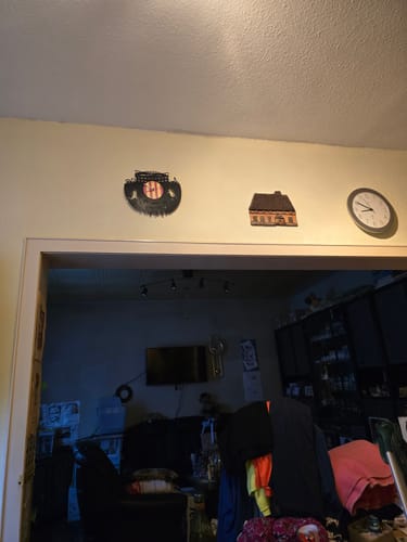 Kunde zeigt die Fussball-Wanduhr aus Vinyl an einer gelben Wand über einer Türöffnung.