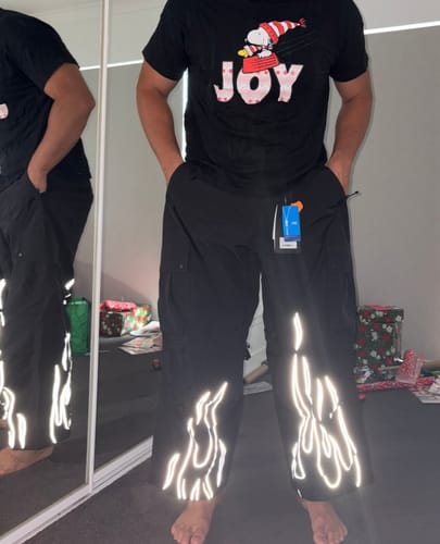 Reviewer wearing black baggy snow pants with reflective flames on the cuffs.