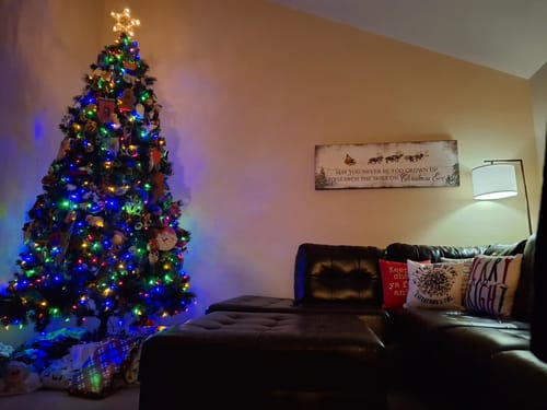 Customer's rustic Christmas Eve sign hanging on a living room wall next to a decorated Christmas tree.