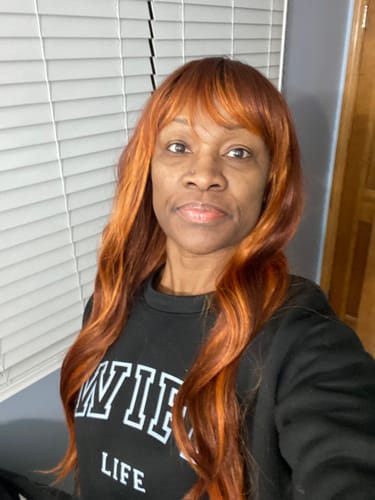 Customer wearing the long, wavy Outre WigPop JUNIPER wig in a vibrant reddish-orange color.