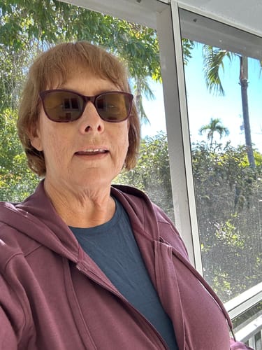 Reviewer outdoors wearing the Ryann Hoodie in Grape Harvest, layered over a blue top.