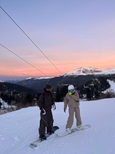 Reviewer on a snowboard showing the fit of the Coffee Techwear Half-Zip Insulated Snow Anorak on a slope.