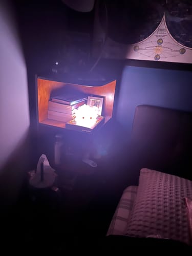 Customer's Axolotl Squishy Night Light glowing brightly on a wooden shelf in a dark bedroom.