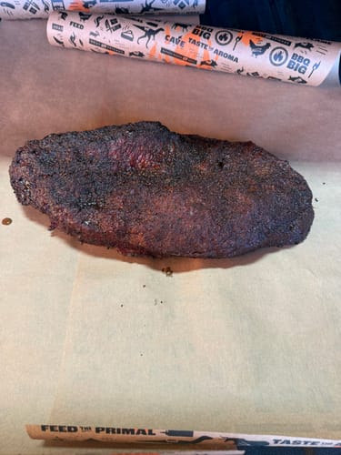 Customer's cooked USDA Prime Brisket with a dark crust resting on butcher paper.