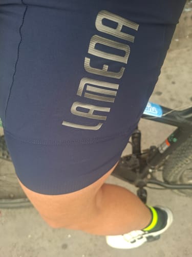 Primer plano de la calza azul Jade Lameda de un cliente, mostrando el logo en el muslo mientras está sobre la bicicleta.