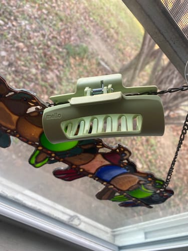 A reviewer's green, matte cloud clip shown from the side against a window.