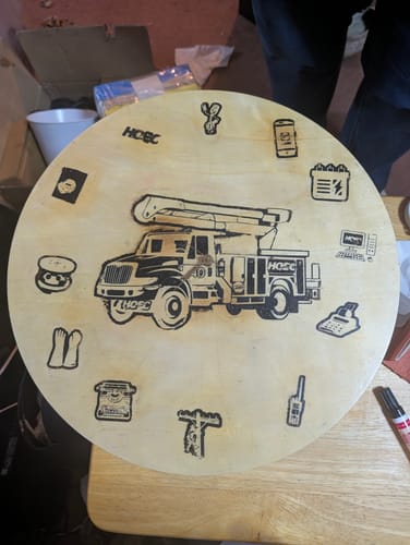 Customer's custom wooden clock with a utility truck and icons burned on using the Scorch Marker Pro.