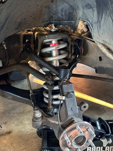 Customer photo showing the new black Upper Control Arm installed on a truck's front suspension.