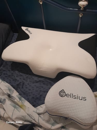 Un client montre son coussin d'alignement cervical Cellsius sur un lit, avec un petit coussin de la marque.