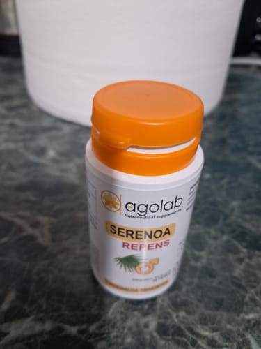 Cliente mostra un flacone bianco di Serenoa Repens di Agolab con tappo arancione su un bancone.