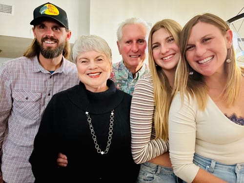 Customer who uses the Grass Fed Tallow & Honey Balm, shown smiling with her family.