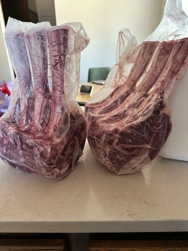 Customer's two raw Tomahawk Prime Rib Roasts in vacuum-sealed packaging sitting on a kitchen counter.