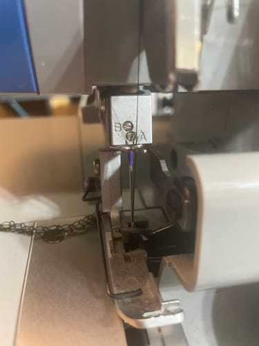 Reviewer's close-up of the Needle Set Screw installed and holding a needle in their serger machine.