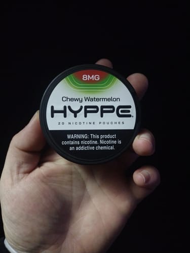 Customer holding a round, black can of HYPPE Chewy Watermelon nicotine pouches in their hand.