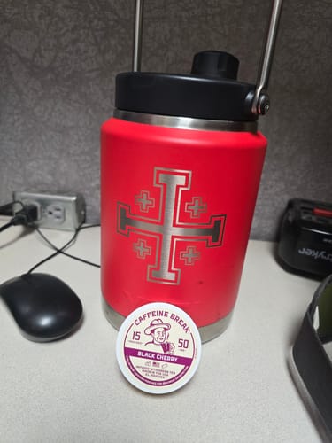 A customer's tin of Black Cherry Caffeine Pouches sitting on a desk next to a red water bottle.