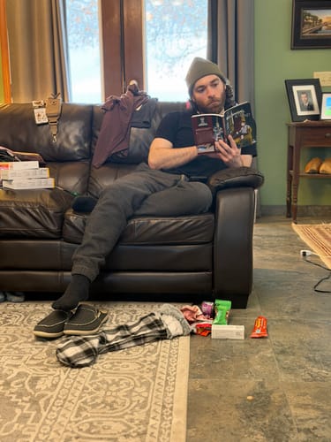 Customer wearing the dark green Big Beanie while sitting on a couch and reading.