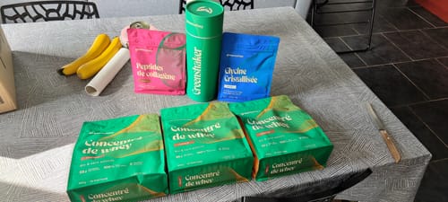 Avis d'un client : trois sachets de Protéine de Whey Bioproduct et d'autres compléments posés sur une table.