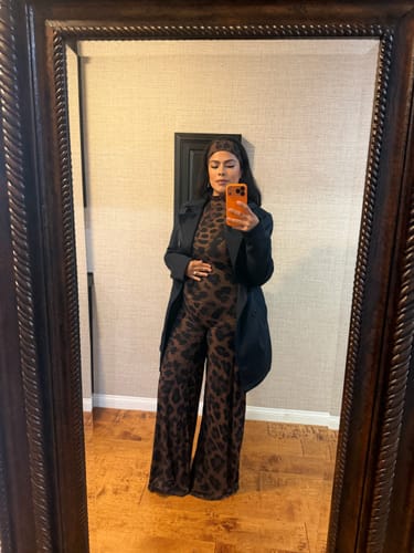 Reviewer in a mirror selfie wearing the Naked Print Wide-Leg Jumpsuit, styled with a black jacket.