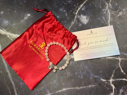 Reviewer's pink beaded bracelet from the VIP Crystal Club next to its red satin pouch and a thank you card.