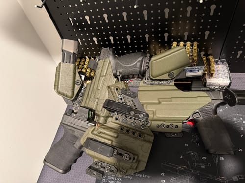 Reviewer's three APX holsters with modular sidecars, displayed with firearms and ammunition.