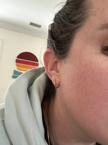 Close-up of a reviewer wearing a gold Eternity Hoop Earring in their ear.