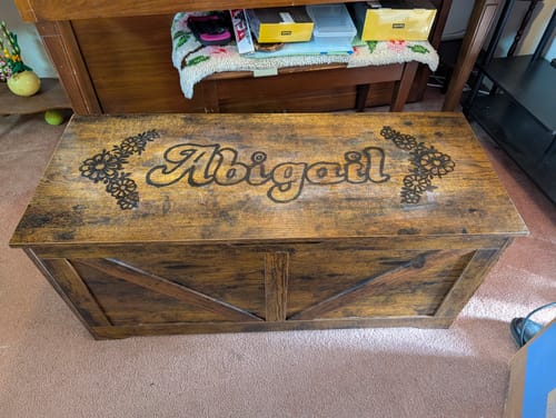 Reviewer's finished project on a wooden chest, with a name and florals burned on using the Paint Brush Bundle.